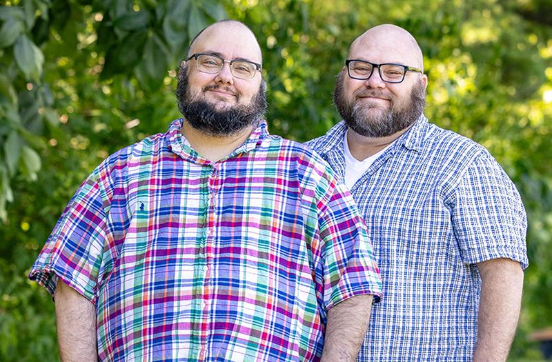 Jonathan Springborn standing next to his husband, Keller, in a park.